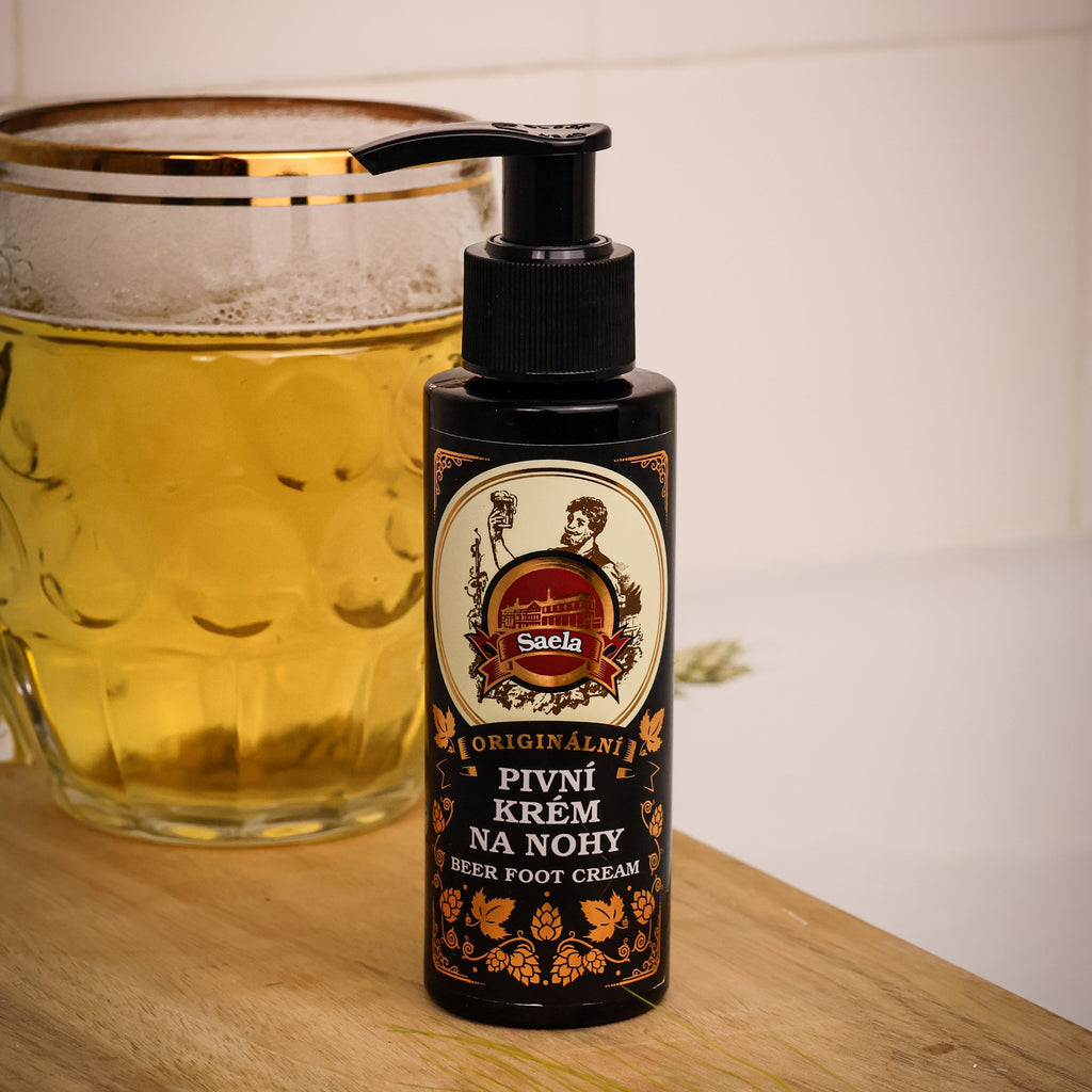 Bottle of foot cream with a label next to a glass of beer on a wooden surface.