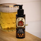 Bottle of foot cream with a label next to a glass of beer on a wooden surface.